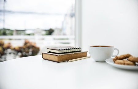 Close-up shot, white coffee cup and cookie for breakfast and take a break with book on white table