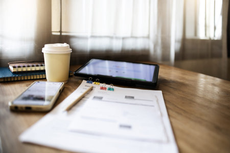 Comfortable workplace on wooden table with coffee cup, mobile phone, tablet and documents. part time...