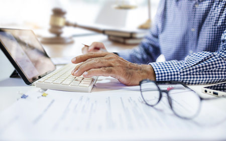Asian businessman using tablet computer working and meeting online at office. legal expert, professional lawyer reading and checking financial documents or insurance contractの写真素材