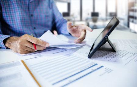 Businessman using tablet working and meeting in office with business documents and contract. lawyer, financial advisor verify the accuracy of documents before giving advice to customersの写真素材