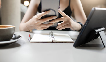 Young asian female tourist in casual clothes black tank top relax in cafe and using mobile phone to...