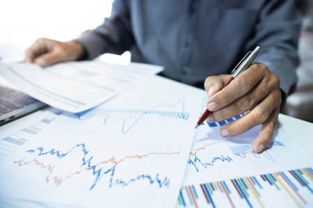 Asian businessman analyzing analyzing investment charts and review business documents, investment planning and business analysis for success concept, close-up viewの写真素材