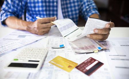 Asian man sitting at desk he holding receipt of expenses worry about find money to pay credit card...