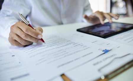Businessman using tablet working in office holding pen verify the accuracy of financial report and...