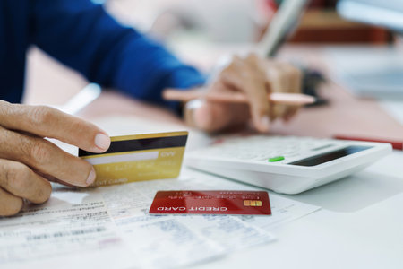 asian man calculate monthly expenses from receipt and many bill of various expenses after spending via credit card and must be pay back soon, close up shotの写真素材