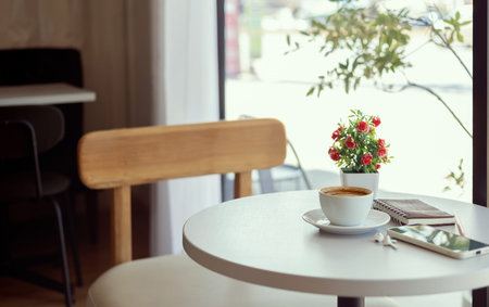 Latte coffee with mobile phone and note book on white table by the window, relax in the morning in...