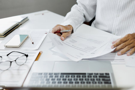 asian businessman reviewing document at office. legal expert, professional lawyer working with laptop reading and checking financial documents and business contractの写真素材