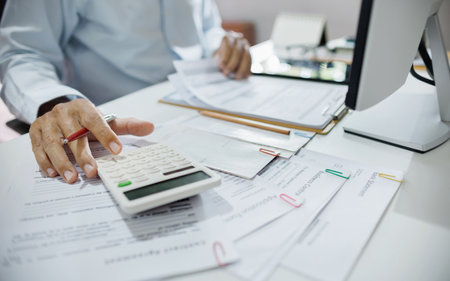 accountants working in office use calculators to calculate business costs, profits and taxの写真素材