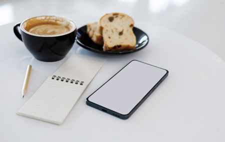 latte coffee with toast for breakfast and working with mobile phone, notebook on white tableの写真素材