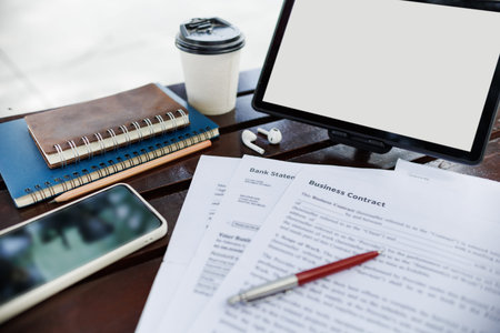 close up shot, digital tablet and business contract, mobile phone, notebook on wooden table in park,...