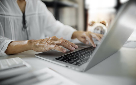 close up shot, housewife in casual clothes working online via laptop at home, asian middle-aged woman start new business onlineの写真素材