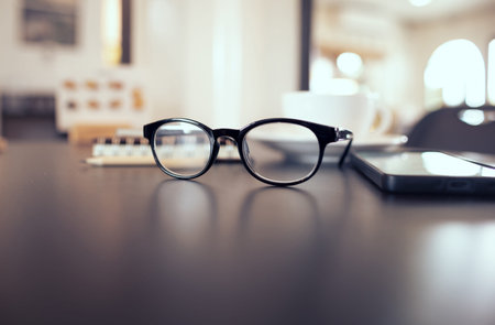 close up, eyeglasses on table with mobile phone, coffee cup, blure background, bokeh and vintage...