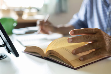 Man reading a book on the table in the office. Close up.