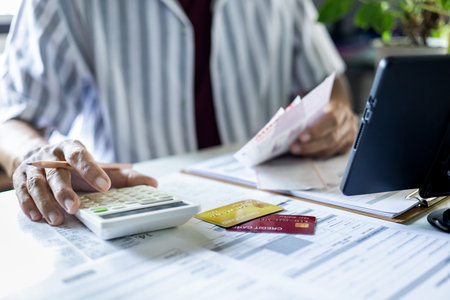 close up shot, asian man calculate expenses from credit card debt and many bills checking bank statement before paying debtの写真素材