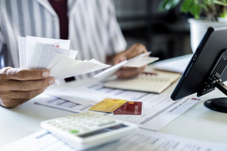 close up shot, asian man holding many receipt and financial bills from spending via credit card and calculate expenses before paying debtの写真素材