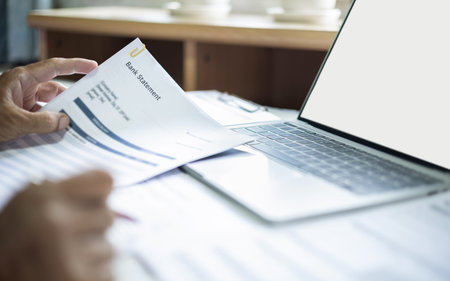 close up shot, asian man working on desk with laptop checking bank statement to apply for business loanの写真素材