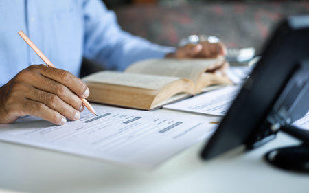 asian man checking business document find knowledge in book using tablet to working online via internet technology, close up shotの写真素材
