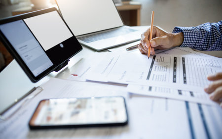 asian man working online via laptop, tablet and mobile phone checking e-commerce form and order from...