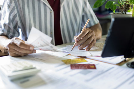 asian man checking receipts and financial bills calculate expenses from credit card debt checking bank statement before paying debtの写真素材