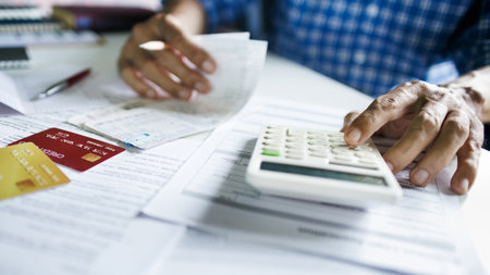 close up shot, asian man calculate expenses from credit card debt and many bills checking bank statement before paying debtの写真素材