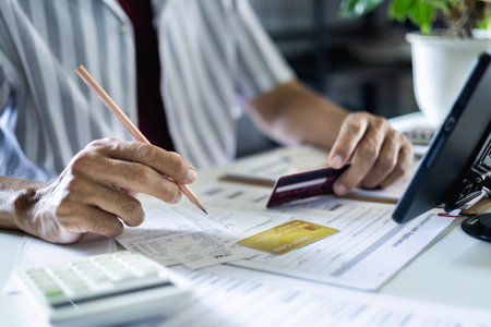 asian man checking receipts and financial bills calculate expenses from credit card debt checking bank statement before paying debtの写真素材
