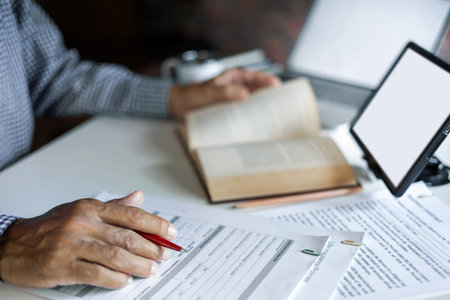 asian man checking business document find knowledge in book using tablet and laptop to working...