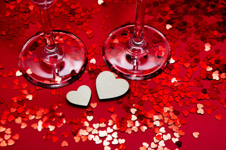 Champagne glasses, wooden hearts and red confetti.の写真素材