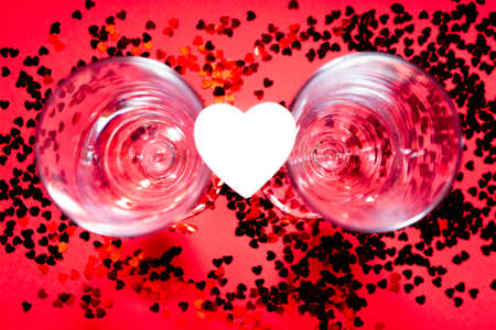 Champagne glasses, wooden hearts and red confetti.の写真素材