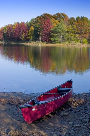 A canoe rests on the shore of a lake in the fallの写真素材