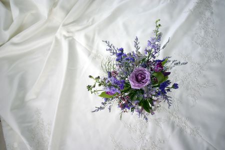 Looking down on a bouquet of flowers and a bride's wedding dress.の写真素材
