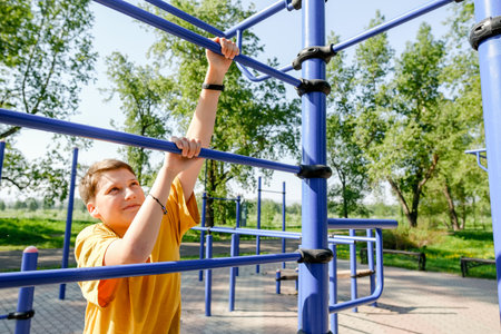 Teen boy have fun on sport stairs playground on park in summer. Time without gadgets concept.