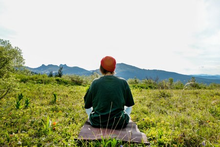 woman doing yoga on a rock, on a background of mountainsの写真素材