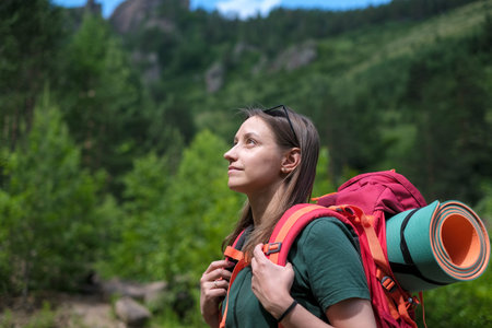 Young female tourist with backpack walking in the forest