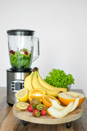 Blender with ingredients for smoothie and products on wooden table in kitchenの写真素材