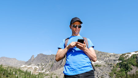 Traveling man using phone to take a photoes in mountain landscape. Blogger takes a selfieの写真素材