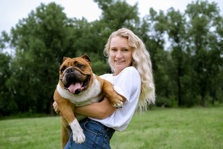 young woman playing with english bulldog at parkの写真素材