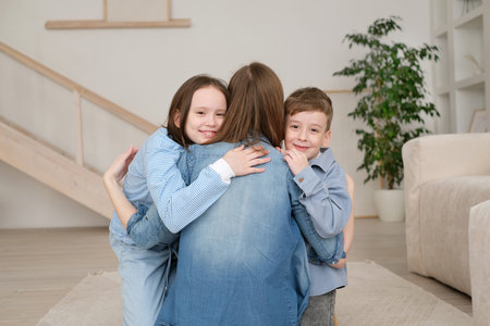 mother with children portrait. Affectionate children embracing young mother, missing her after long separation. Loving mommy kids, relaxing together on comfortable couch in living room.の写真素材