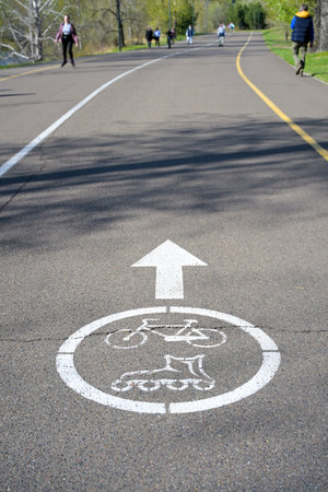 white sign for cyclists and rollerbladers on asphalt path in parkの写真素材