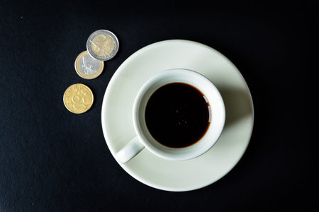 A coffee cup and Euro coins on back backgronud
