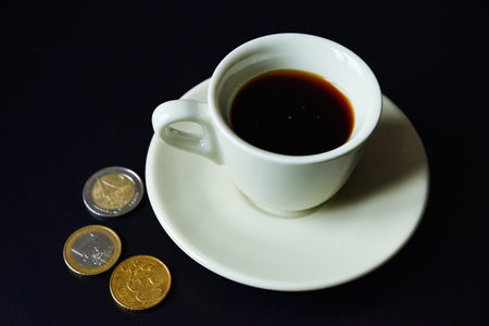 A coffee cup and Euro coins on back backgronudの写真素材