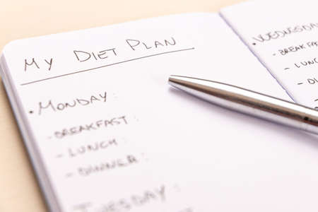 Diet plan: planning of the weekly diet, with the foods to eat during the week, written on a white notebook with black ink.の写真素材