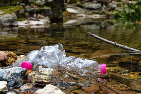 Plastic bottles thrown into the bed of a stream, floating in the water. Water pollution.