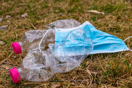 Plastic bottles and surgical mask, thrown along a mountain path, in the middle of the grass....