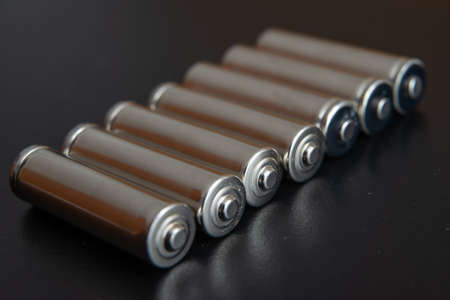 Batteries arranged side by side, on a dark surface. Batteries, energy and respect for the environment. Alkaline or rechargeable batteries.の写真素材