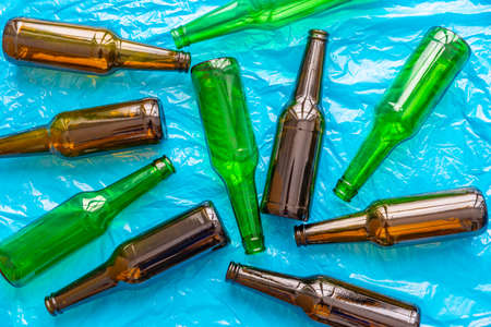 Empty beer or beverage bottles on blue surface. Reuse and recycling of glass. Waste.の写真素材