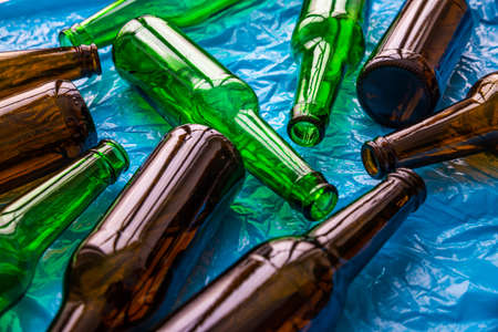 Empty beer or beverage bottles on blue surface. Reuse and recycling of glass. Waste.の写真素材