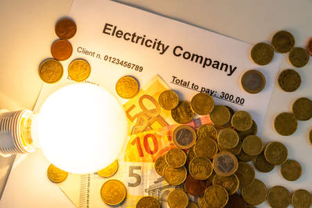 Light bulb on, with banknotes, coins and energy bill. Increase in energy and gas tariffs. Efficiency and energy saving.の写真素材