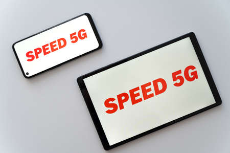 Phone and tablet, with "speed 5g" text in red, on the screen. New 5g data transmission standard.の写真素材