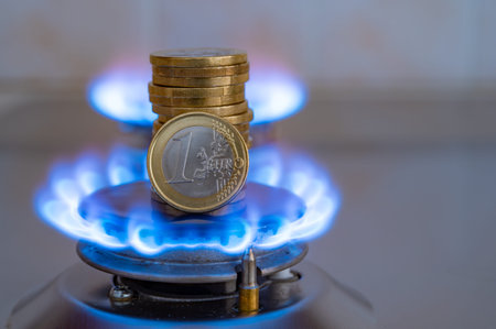 Gas stove lit, with stacks of coins above it. Increase in gas costs and tariffs.
