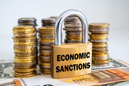 Padlock with "economic sanctions" text next to money. Economic sanctions, economic retaliation against the war.の写真素材